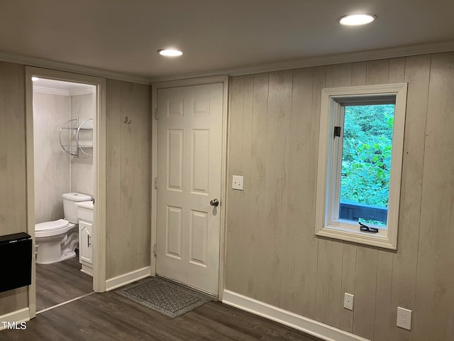 unfurnished bedroom with dark wood-type flooring, wood walls, and ensuite bathroom