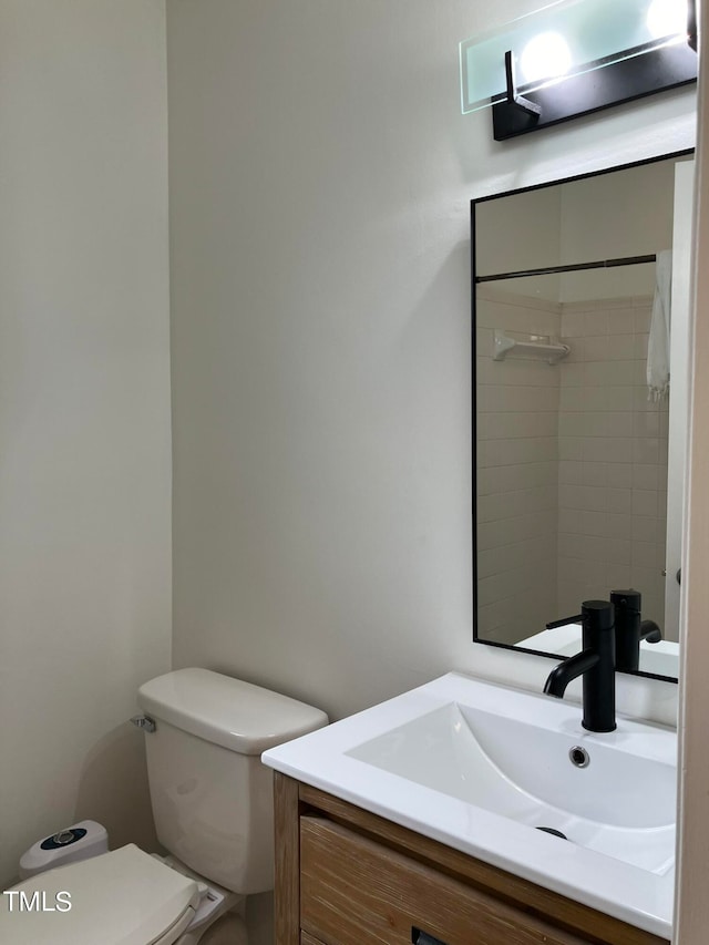 bathroom featuring toilet, a tile shower, and vanity