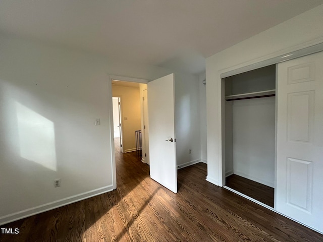 unfurnished bedroom featuring a closet and dark hardwood / wood-style flooring