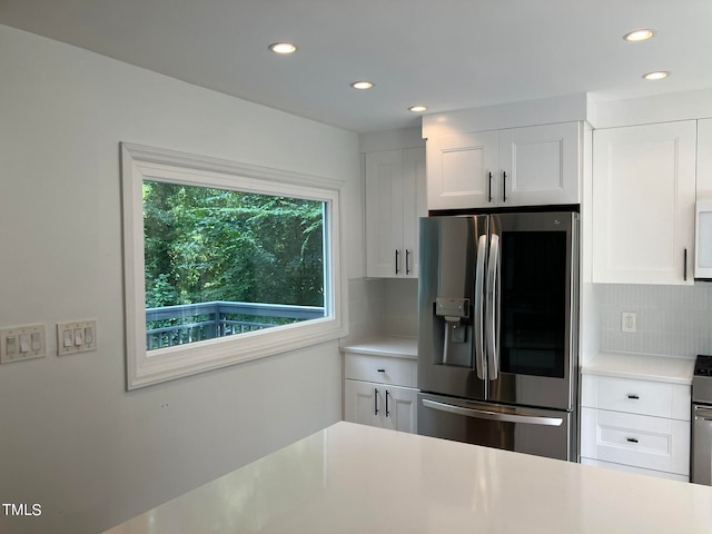 kitchen with white cabinets, stainless steel fridge, and backsplash