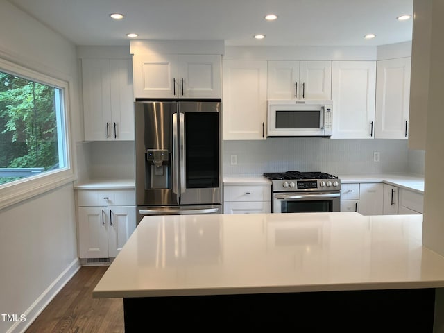 kitchen featuring dark wood-type flooring, stainless steel appliances, white cabinets, and tasteful backsplash