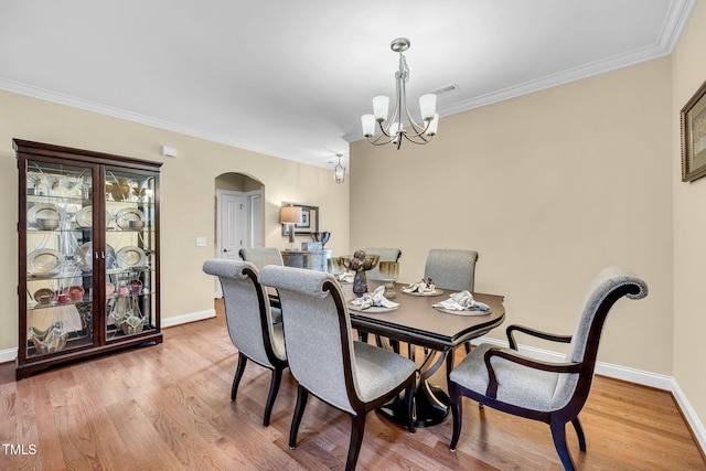 dining space featuring light wood-type flooring, baseboards, arched walkways, and a notable chandelier