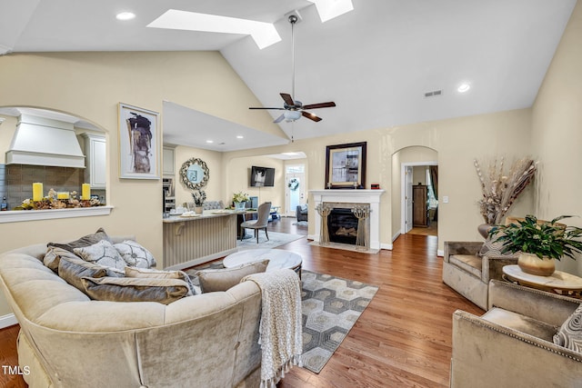 living area with a skylight, visible vents, a fireplace with flush hearth, light wood-style flooring, and recessed lighting