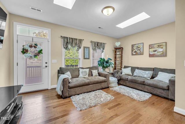 living room featuring a skylight, visible vents, and wood finished floors