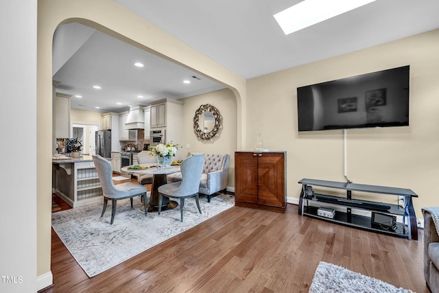 dining space with light wood-style flooring, arched walkways, baseboards, and recessed lighting