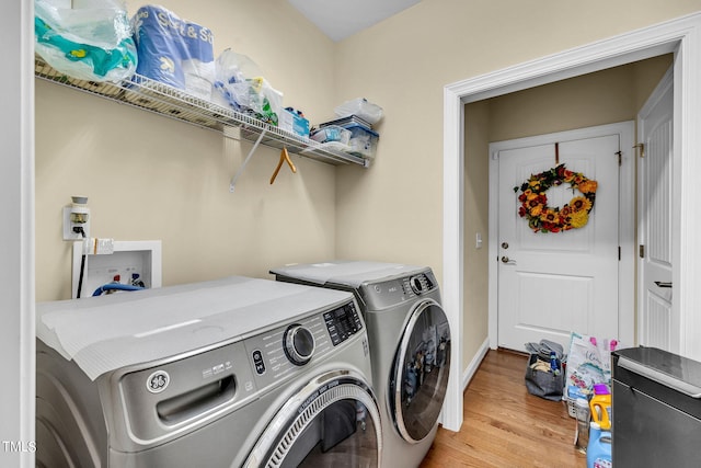 washroom with laundry area, light wood finished floors, washing machine and clothes dryer, and baseboards