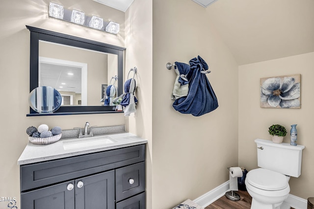 bathroom featuring baseboards, toilet, wood finished floors, vaulted ceiling, and vanity