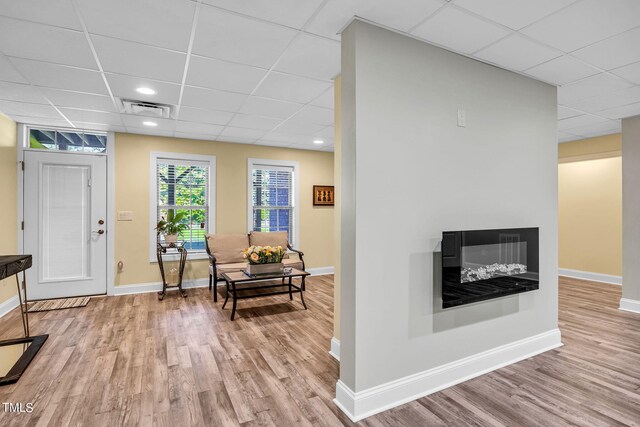 interior space with light wood-type flooring, baseboards, visible vents, and a multi sided fireplace