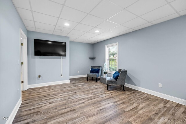 sitting room featuring a paneled ceiling, baseboards, and wood finished floors