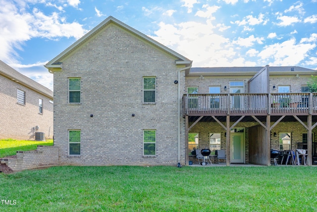 rear view of property featuring a yard, brick siding, a wooden deck, and central air condition unit