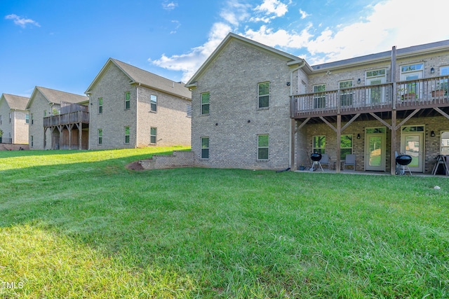 rear view of house with brick siding, a lawn, and a deck