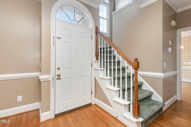 entrance foyer with crown molding and light hardwood / wood-style flooring