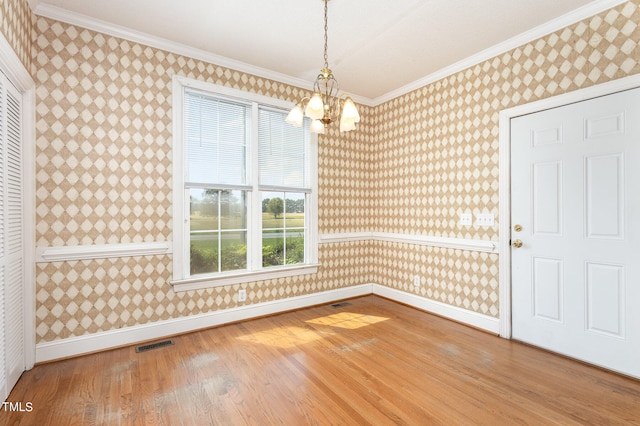 unfurnished dining area featuring wood-type flooring, a notable chandelier, and ornamental molding