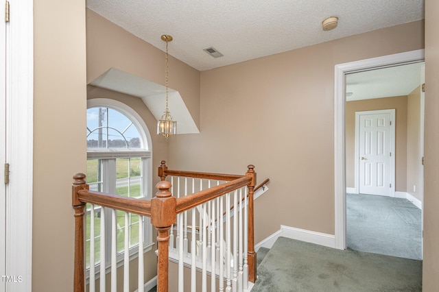 corridor featuring a textured ceiling and carpet