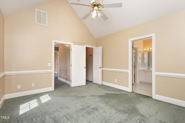 unfurnished bedroom featuring high vaulted ceiling, ceiling fan, carpet, and ensuite bath