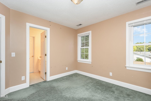 carpeted empty room with a textured ceiling