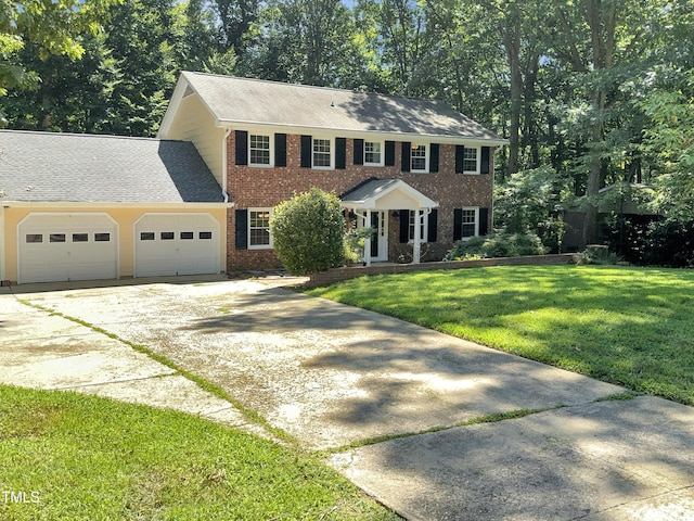 colonial house with a garage, concrete driveway, brick siding, and a front lawn