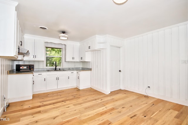 kitchen with white cabinetry, sink, exhaust hood, and light hardwood / wood-style floors