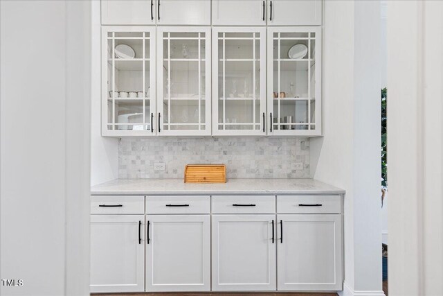 bar featuring light stone counters, white cabinetry, and tasteful backsplash