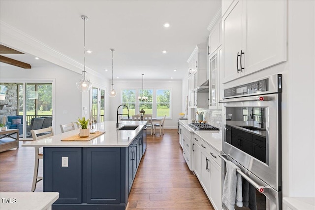 kitchen with a breakfast bar area, a spacious island, stainless steel appliances, sink, and white cabinets