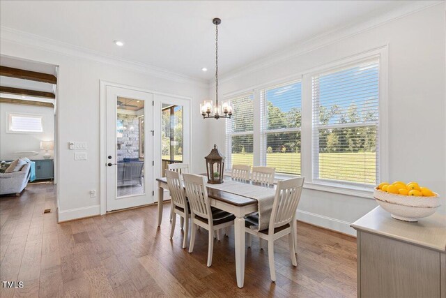 dining room featuring hardwood / wood-style flooring, beam ceiling, a chandelier, and ornamental molding