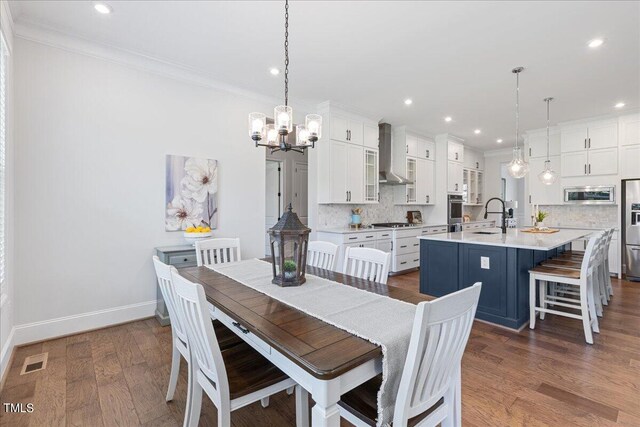 dining room featuring crown molding, sink, a chandelier, and dark hardwood / wood-style flooring