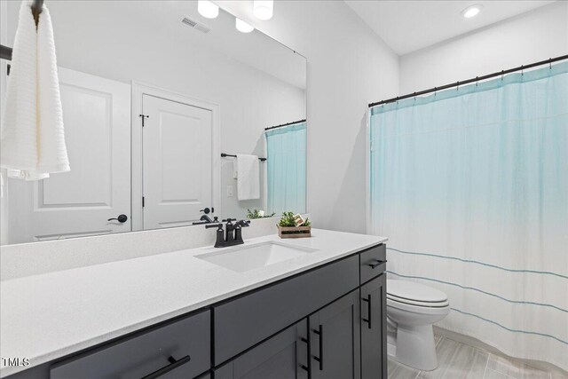 bathroom with walk in shower, toilet, and vanity