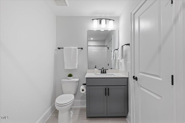 bathroom with vanity, toilet, tiled shower, and tile patterned flooring