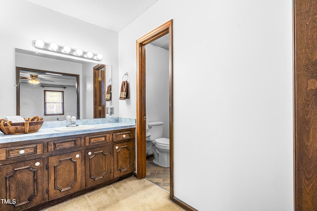 bathroom with toilet, vanity, and ceiling fan