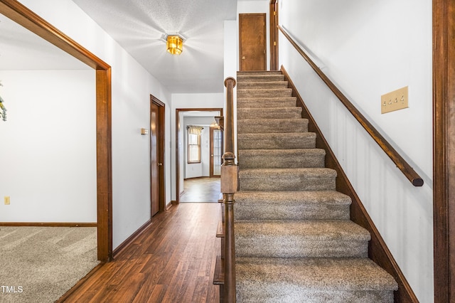 stairs with a textured ceiling and hardwood / wood-style floors