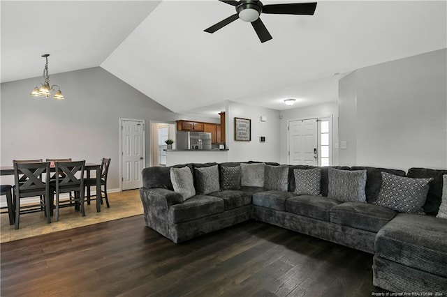 living room with dark wood-type flooring, a healthy amount of sunlight, ceiling fan with notable chandelier, and vaulted ceiling