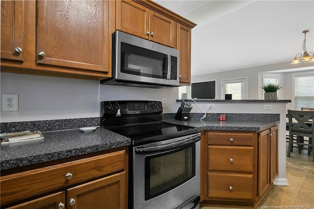 kitchen with appliances with stainless steel finishes, a chandelier, kitchen peninsula, and dark stone counters