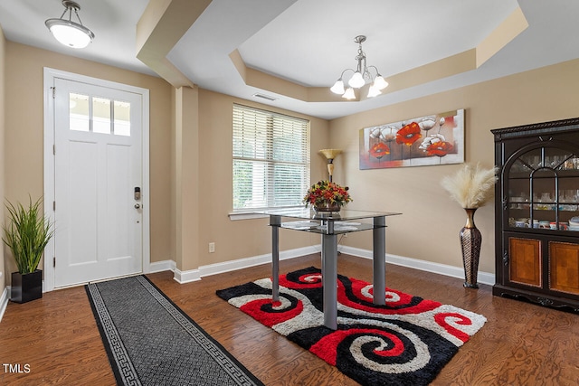 entrance foyer with dark hardwood / wood-style floors, a notable chandelier, and a tray ceiling