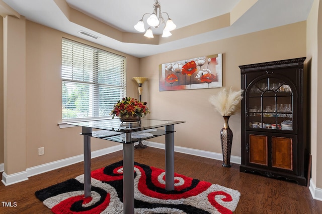 dining area featuring a notable chandelier, a raised ceiling, and dark hardwood / wood-style floors