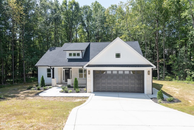 modern farmhouse with a front lawn, covered porch, concrete driveway, an attached garage, and a shingled roof