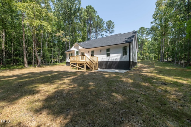 back of property featuring a wooden deck and a yard