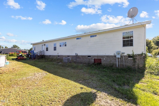 rear view of house featuring central AC unit and a lawn