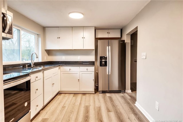 kitchen with light wood-type flooring, appliances with stainless steel finishes, white cabinetry, and sink