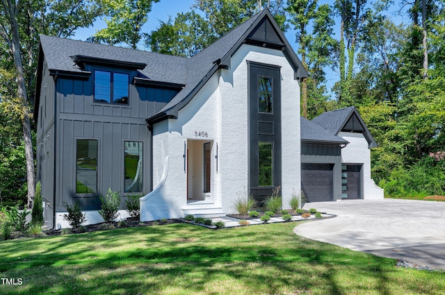 modern farmhouse style home with a front lawn, driveway, board and batten siding, a shingled roof, and an attached garage