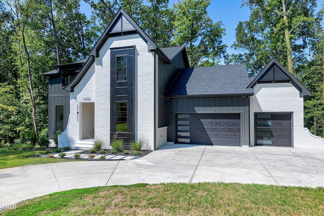 view of front of house featuring driveway, board and batten siding, a shingled roof, and a garage