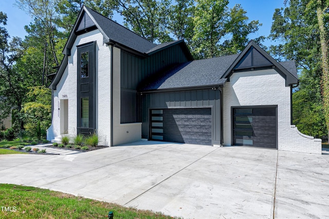 view of front facade with concrete driveway, an attached garage, board and batten siding, and a shingled roof