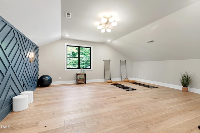 exercise area with light wood finished floors, baseboards, vaulted ceiling, and visible vents