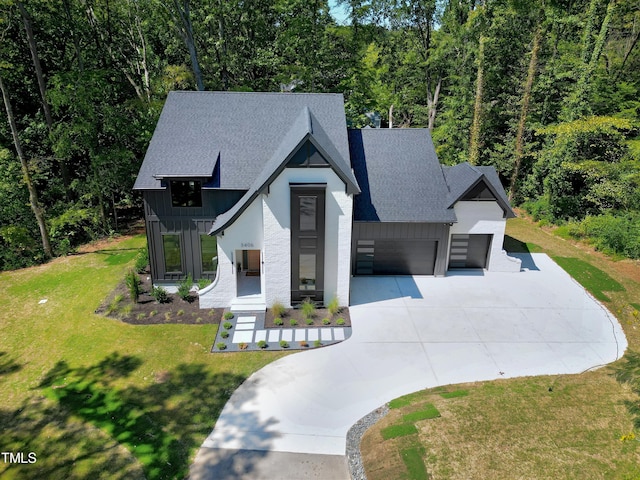 view of front of house featuring concrete driveway, board and batten siding, a shingled roof, an attached garage, and a front yard