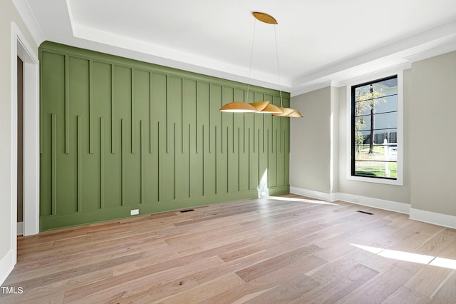 unfurnished dining area with light hardwood / wood-style flooring and a tray ceiling