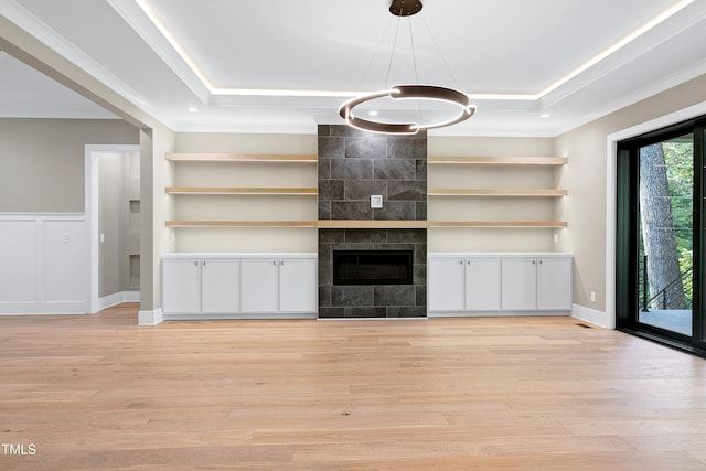 unfurnished living room featuring built in features, light wood-type flooring, and a tile fireplace