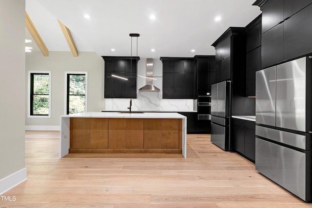 kitchen featuring high end refrigerator, a kitchen island with sink, beam ceiling, light hardwood / wood-style flooring, and hanging light fixtures