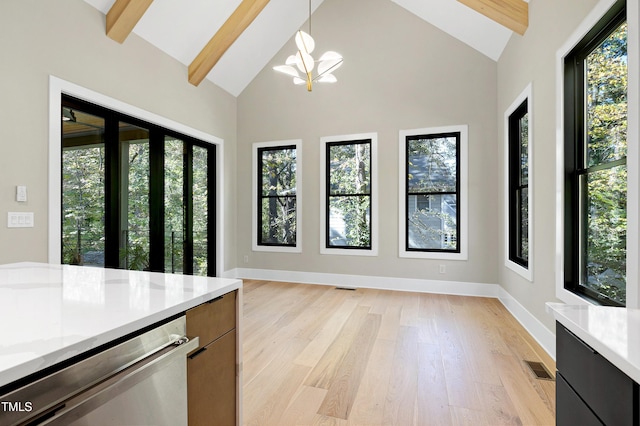 kitchen with beamed ceiling, light wood-type flooring, decorative light fixtures, and a healthy amount of sunlight