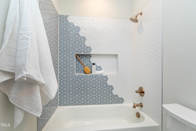 bathroom with toilet and tiled shower / bath