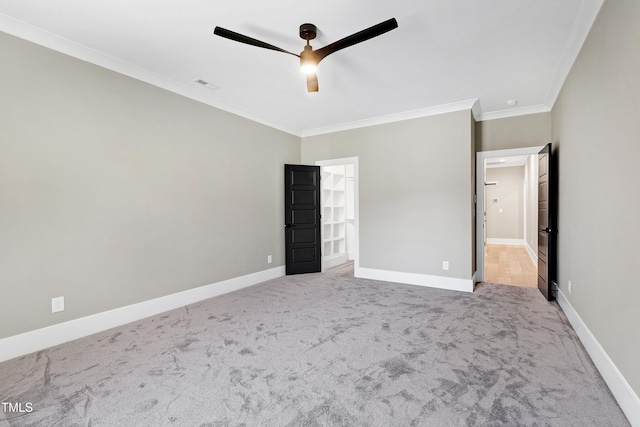 unfurnished bedroom featuring a spacious closet, ornamental molding, light colored carpet, and ceiling fan