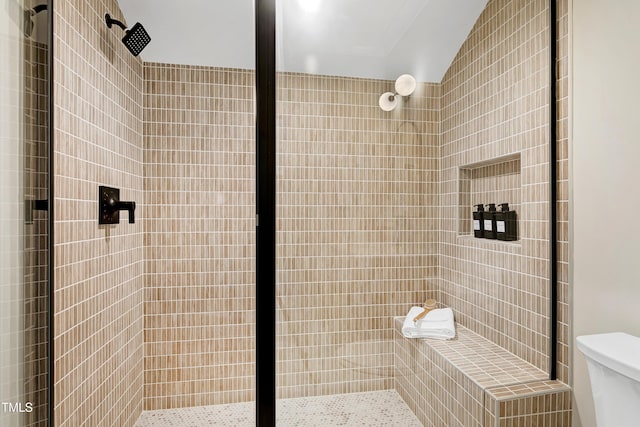 bathroom featuring a shower with door and toilet